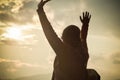 Beautiful fashionable woman enjoying holiday in sunset sun of orange sky background, raise hands up in air close up, back view