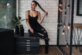 Beautiful fashionable woman at loft style room with white bricks wall and black iron net. Attractive girl with perfect