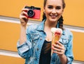 Beautiful fashionable young girl posing in a summer dress and denim jacket with pink vintage camera and multi-colored ice cream. Royalty Free Stock Photo