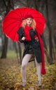 Beautiful fashionable young girl with red umbrella , red cap and red scarf in the park Royalty Free Stock Photo