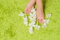 Beautiful feet with pedicure and flowers at green background Royalty Free Stock Photo