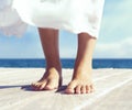 Beautiful feet of a woman in white dress on a wooden pier. Sea Royalty Free Stock Photo