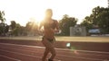 Beautiful female athlete runnung, working out in the morning on the stadium. Wearing black bikini and white sneakers