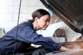 Beautiful female auto mechanic in uniform working with engine vehicle at garage, car service technician woman checking and Royalty Free Stock Photo