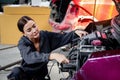 Female auto mechanic in uniform work with engine vehicle at garage, technician woman repairing customer car at automobile service Royalty Free Stock Photo