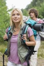 Beautiful female backpacker looking away with man standing in background at forest