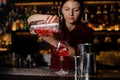 Beautiful female barman pouring sweet red alcoholic drink into a Royalty Free Stock Photo