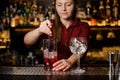 Beautiful female barman stirring sweet alcoholic drink with ice