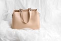 Beautiful female beige handbag on white background with soft material. spring fashion concept, copy space