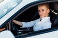 Beautiful female blonde driver behind the wheel of a white car Royalty Free Stock Photo