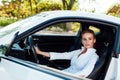 Beautiful female blonde driver behind the wheel of a white car Royalty Free Stock Photo