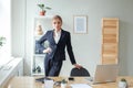 Beautiful female business woman CEO in a black suit at the workplace in office, standing confidently with arms folded Royalty Free Stock Photo