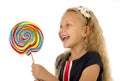 Beautiful female child with long blond hair holding huge spiral lollipop candy smiling happy Royalty Free Stock Photo
