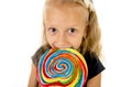 Beautiful female child with long blond hair holding huge spiral lollipop candy smiling happy Royalty Free Stock Photo