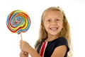 Beautiful female child with long blond hair holding huge spiral lollipop candy smiling happy Royalty Free Stock Photo