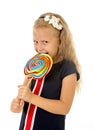 Beautiful female child with long blond hair holding huge spiral lollipop candy smiling happy Royalty Free Stock Photo