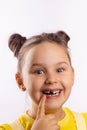 Beautiful female child with opened mouth showing missing front milk tooth with finger on bottom lip smiling excitedly on Royalty Free Stock Photo