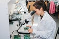 Beautiful female computer expert professional technician examining board computer in a laboratory in a factory