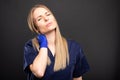 Beautiful female dentist wearing scrubs making neck pain gesture Royalty Free Stock Photo