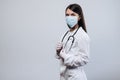 Beautiful female doctor or nurse wearing protective mask and latex or rubber gloves on grey background with copyspace. Royalty Free Stock Photo