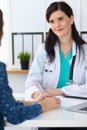 Beautiful female doctor and patient having a talk while sitting at the desk. Physician writes prescription with silver Royalty Free Stock Photo