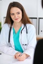 Beautiful female doctor and patient having a talk while sitting at the desk. Physician writes prescription with silver Royalty Free Stock Photo