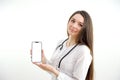 Beautiful female doctor smiling and showing a blank smart phone screen isolated on a white background. Portrait of happy Royalty Free Stock Photo