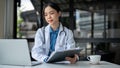 A beautiful female doctor is working at her desk in the hospital, reading medical reports online Royalty Free Stock Photo