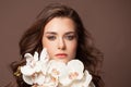 Beautiful female face with healthy brown hair, clear skin and white orchid flowers portrait Royalty Free Stock Photo