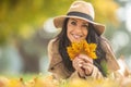 Beautiful female in fashionwear holds autumn leaves lying on the ground