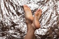 Beautiful female feet on a beautiful background in the form of a foil. Fashionable photo of female legs. Red pedicure