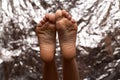 Beautiful female feet on a beautiful background in the form of a foil. Fashionable photo of female legs. Red pedicure