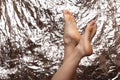 Beautiful female feet on a beautiful background in the form of a foil. Fashionable photo of female legs. Red pedicure