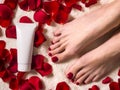 Beautiful female feet with a beautiful pedicure with a tube of cream on a terry towel with rose petals. Spa and skin Royalty Free Stock Photo