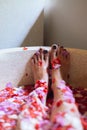 Beautiful female feet in outdoor bath with tropical flowers.Spa,organic and skin care concept. Woman legs in petals. Royalty Free Stock Photo