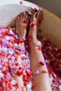 Beautiful female feet in outdoor bath with tropical flowers.Spa and skin care concept. Woman legs in petals Royalty Free Stock Photo