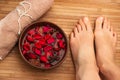 Beautiful female feet, spa salon, pedicure procedure with petals of red rose flower Royalty Free Stock Photo