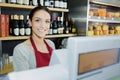 Beautiful female food store employee at cashier smiling
