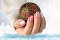 Beautiful female hand with christmas nail design. Hand with elegant pink nail manicure holding a red christmas decoration ball. S Royalty Free Stock Photo