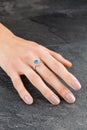 Beautiful female hand with gold ring with diamonds and aquamarine on gray background