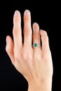 Beautiful female hand with gold ring with diamonds and emerald on black background