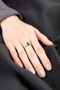 Beautiful female hand with gold ring with diamonds and emerald on gray background