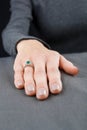 Beautiful female hand with gold ring with diamonds and emerald on gray background