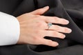 Beautiful female hand with gold ring with diamonds and emerald on gray background