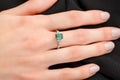 Beautiful female hand with gold ring with diamonds and emerald on gray background Royalty Free Stock Photo
