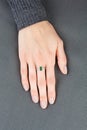 Beautiful female hand with gold ring with diamonds and emerald on gray background