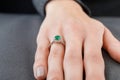 Beautiful female hand with gold ring with diamonds and emerald on gray background