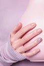 Beautiful female hand holding pink vase on the pale violet background. Manicure with pink color nail polish with shiny design,
