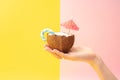 A beautiful female hand holds half a coconut with a lollipop and umbrella. Summer refreshing drink. Royalty Free Stock Photo