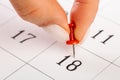 Beautiful female Hand with manicure pushes a red pin on a calendar 18 day Royalty Free Stock Photo